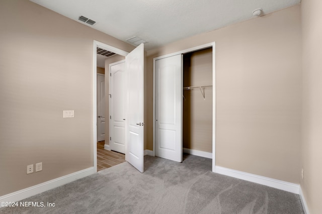 unfurnished bedroom featuring a closet and light colored carpet