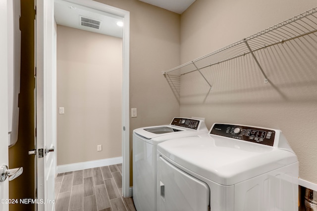 washroom with light wood-type flooring and washing machine and clothes dryer