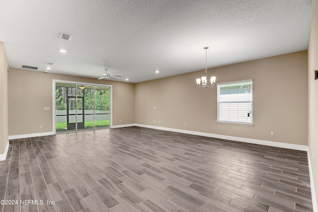 empty room featuring wood-type flooring, ceiling fan with notable chandelier, and a textured ceiling