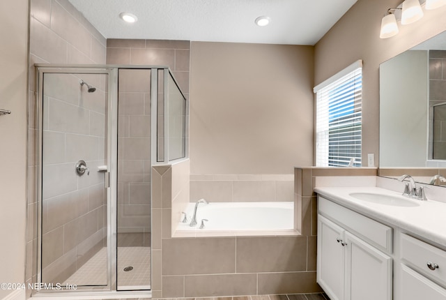 bathroom with plus walk in shower, a textured ceiling, and vanity