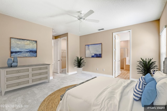 bedroom with a walk in closet, light colored carpet, ceiling fan, connected bathroom, and a closet