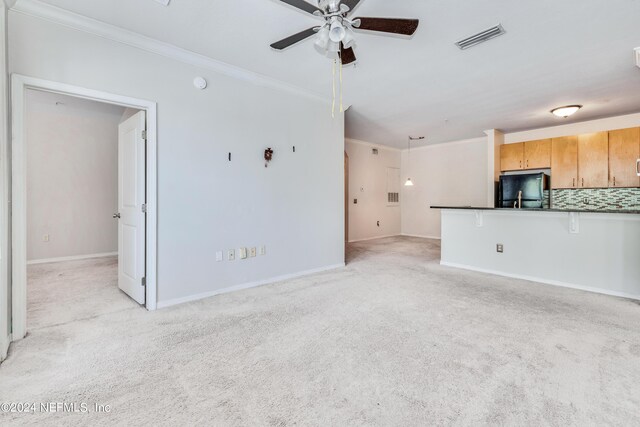 unfurnished living room featuring ceiling fan, light colored carpet, and ornamental molding