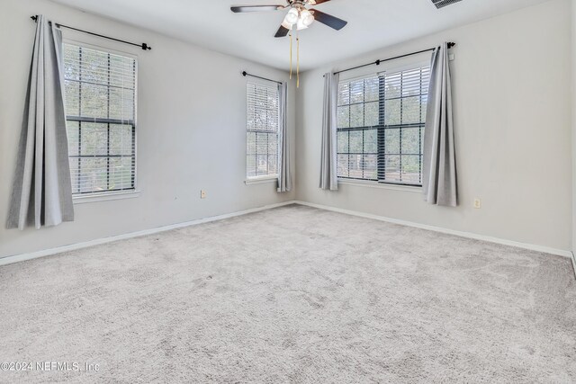 spare room with light carpet, a wealth of natural light, and ceiling fan