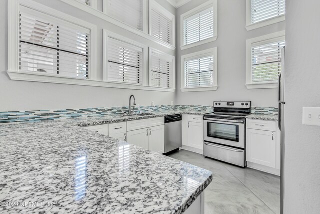 kitchen with white cabinetry, sink, light stone counters, and stainless steel appliances