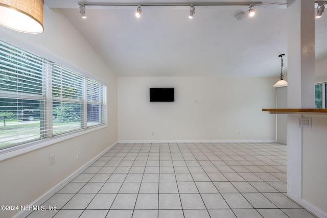 unfurnished living room with rail lighting, vaulted ceiling, and a wealth of natural light