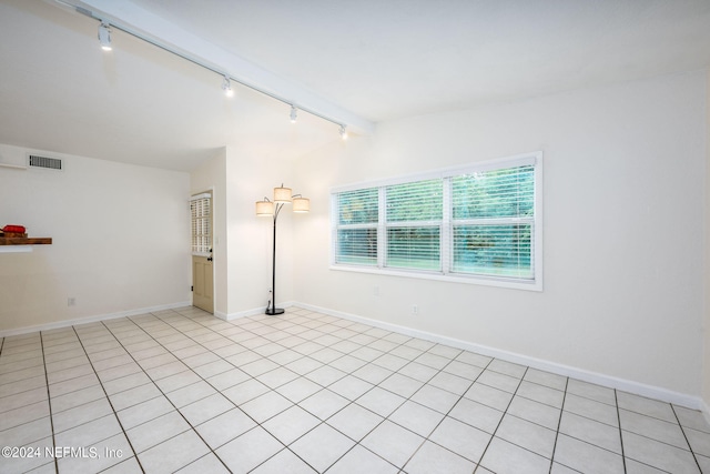 tiled spare room featuring lofted ceiling with beams and rail lighting