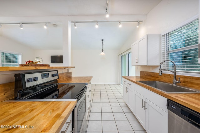 kitchen with hanging light fixtures, sink, white cabinetry, appliances with stainless steel finishes, and wood counters