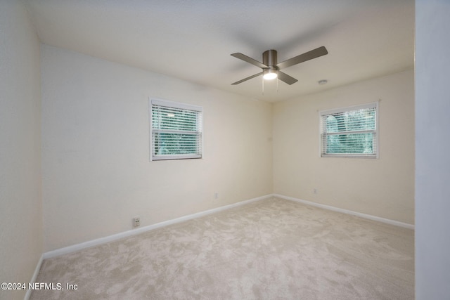 spare room with ceiling fan, light colored carpet, and plenty of natural light