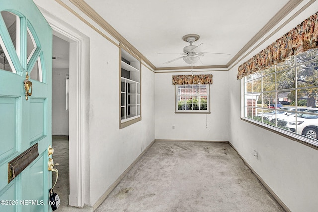 empty room with ceiling fan, baseboards, crown molding, and carpet flooring