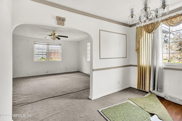 carpeted empty room featuring crown molding, arched walkways, plenty of natural light, and ceiling fan with notable chandelier