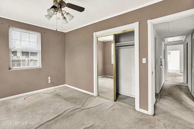 unfurnished bedroom featuring carpet, a closet, attic access, ornamental molding, and baseboards