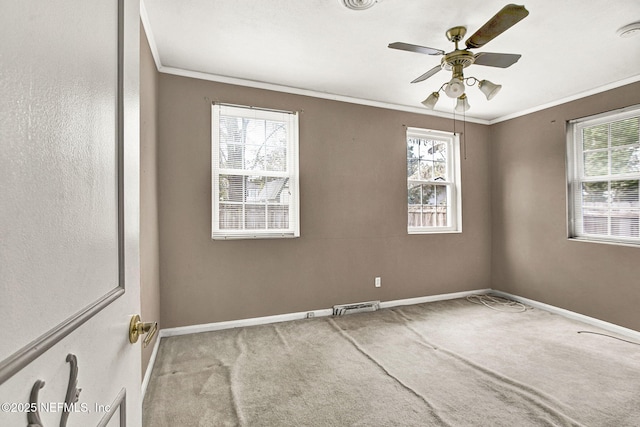 spare room featuring carpet, ornamental molding, plenty of natural light, and visible vents