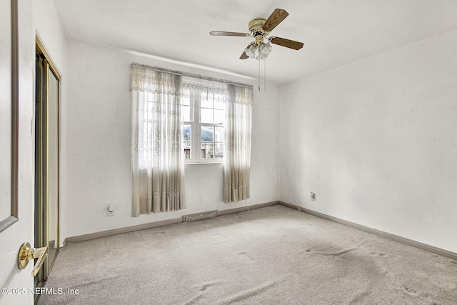 carpeted empty room with a ceiling fan and baseboards