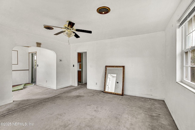 spare room featuring carpet floors, visible vents, arched walkways, and a ceiling fan