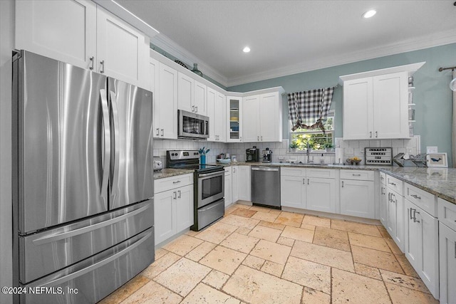 kitchen with light stone counters, white cabinetry, backsplash, appliances with stainless steel finishes, and crown molding