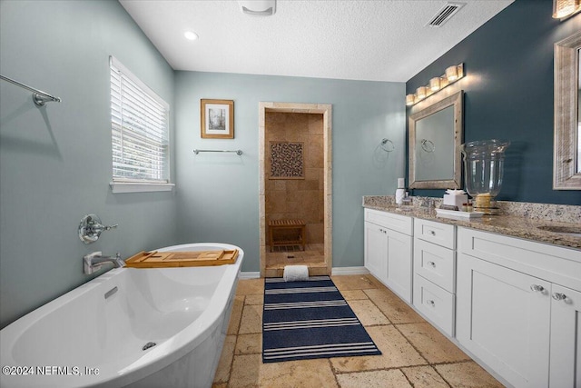 bathroom featuring a textured ceiling, vanity, and separate shower and tub