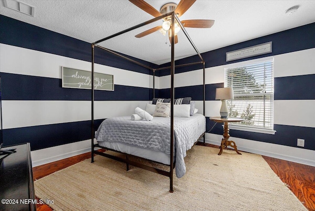 bedroom with wood-type flooring, ceiling fan, and a textured ceiling