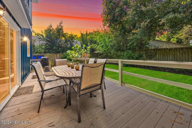 deck at dusk featuring a lawn