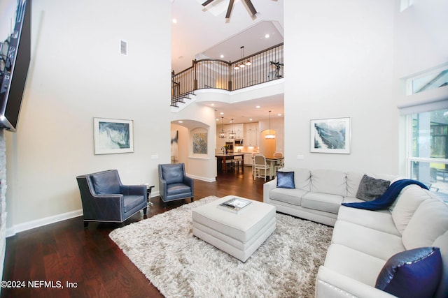 living room featuring ceiling fan, a towering ceiling, and dark hardwood / wood-style flooring