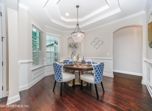 dining room with a raised ceiling, ornamental molding, dark hardwood / wood-style floors, and a notable chandelier