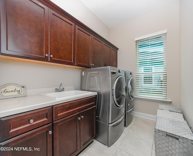 laundry room featuring cabinets, light tile patterned flooring, washer and clothes dryer, and sink