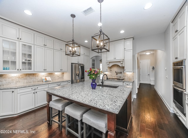 kitchen featuring a chandelier, dark hardwood / wood-style floors, an island with sink, white cabinetry, and stainless steel appliances