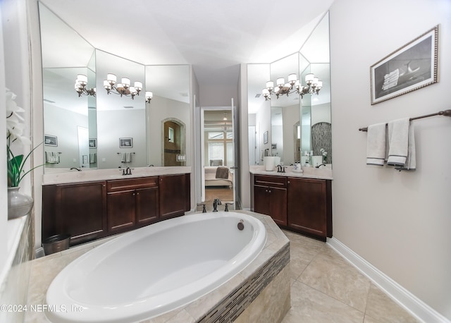 bathroom with a notable chandelier, vanity, tiled bath, and tile patterned flooring