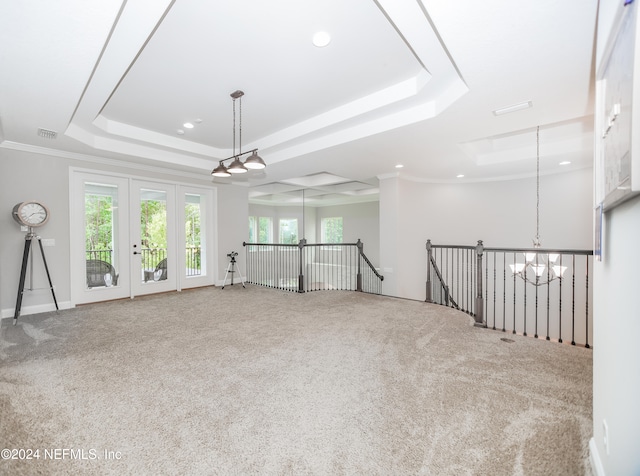 carpeted spare room with crown molding, a tray ceiling, and an inviting chandelier