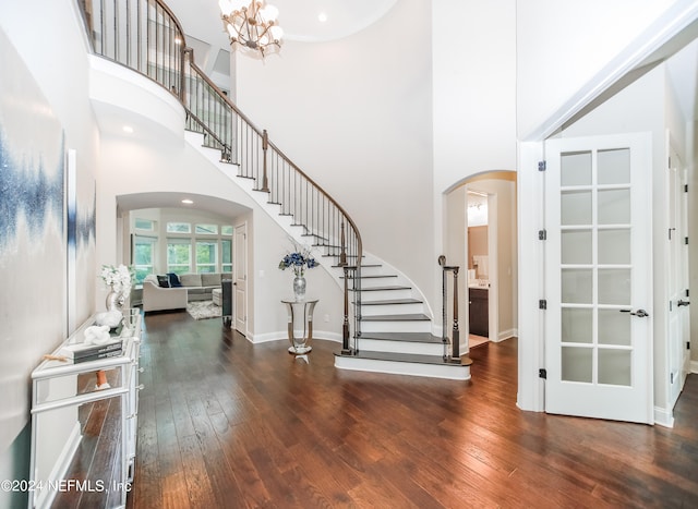 entryway featuring a towering ceiling, a chandelier, and dark wood-type flooring