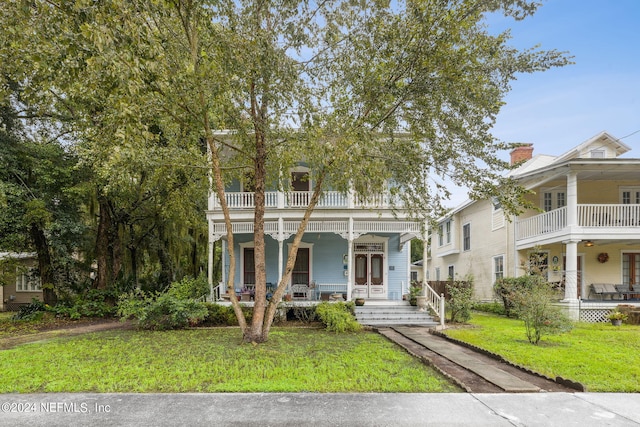 view of front of property with a balcony, covered porch, and a front yard