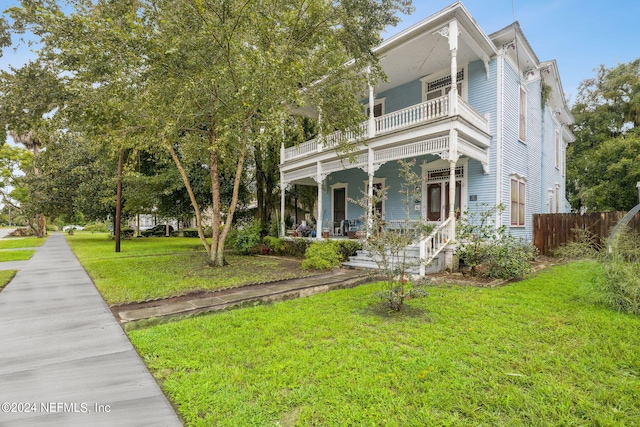 view of front of home with a balcony, a porch, and a front yard