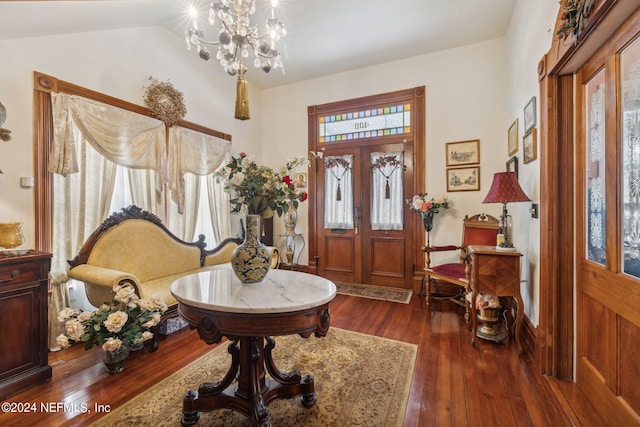 foyer entrance featuring a notable chandelier, vaulted ceiling, and dark hardwood / wood-style floors