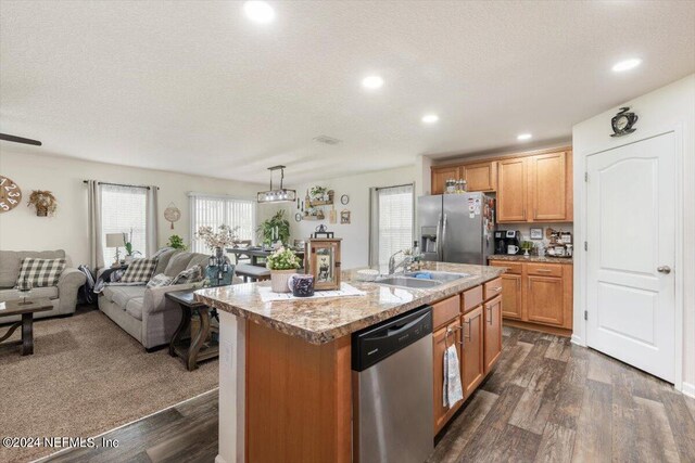 kitchen with a center island with sink, appliances with stainless steel finishes, dark hardwood / wood-style floors, and decorative light fixtures