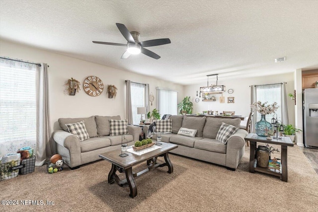 carpeted living room with ceiling fan and a textured ceiling