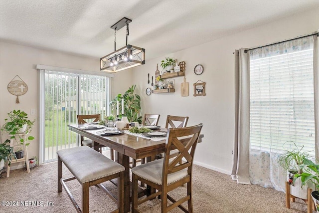 dining space featuring light colored carpet, a textured ceiling, and a chandelier