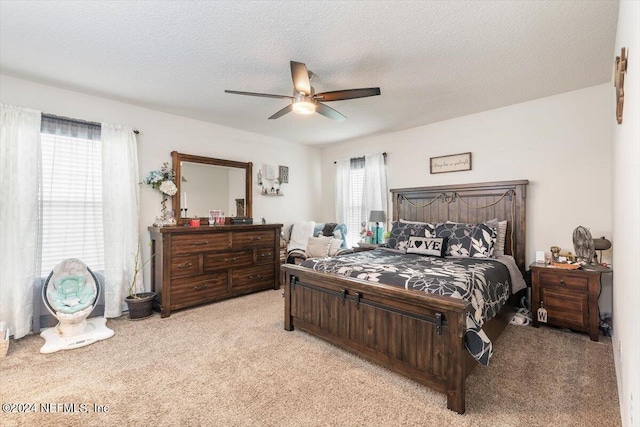 carpeted bedroom featuring ceiling fan, a textured ceiling, and multiple windows