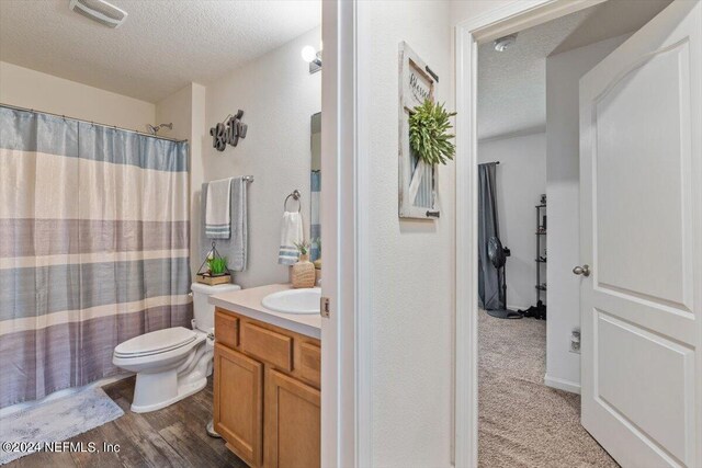 bathroom featuring a textured ceiling, wood-type flooring, vanity, and toilet