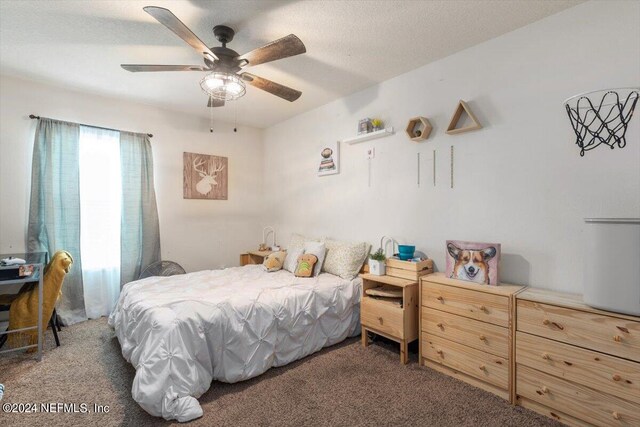 carpeted bedroom featuring ceiling fan and a textured ceiling