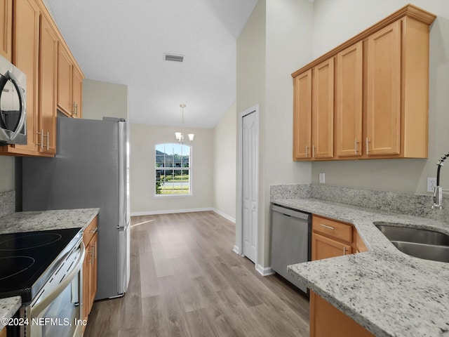 kitchen with sink, hanging light fixtures, light wood-type flooring, light stone counters, and stainless steel appliances