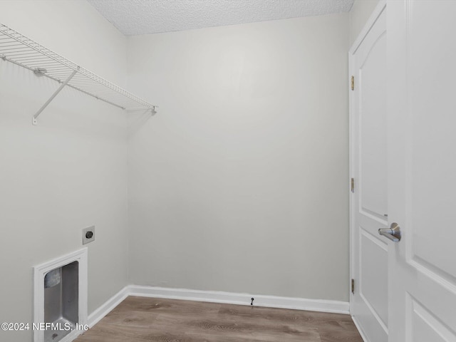 clothes washing area with hookup for an electric dryer, light wood-type flooring, and a textured ceiling