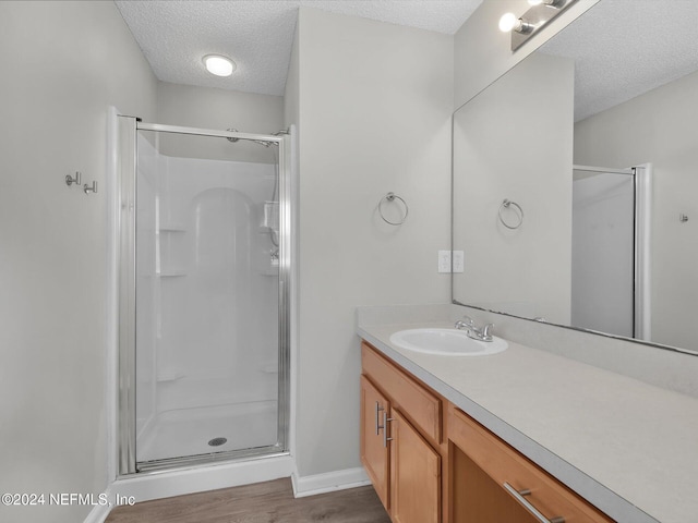 bathroom with walk in shower, vanity, a textured ceiling, and hardwood / wood-style flooring