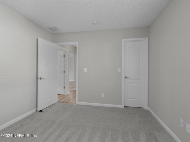 unfurnished bedroom with light carpet and a textured ceiling