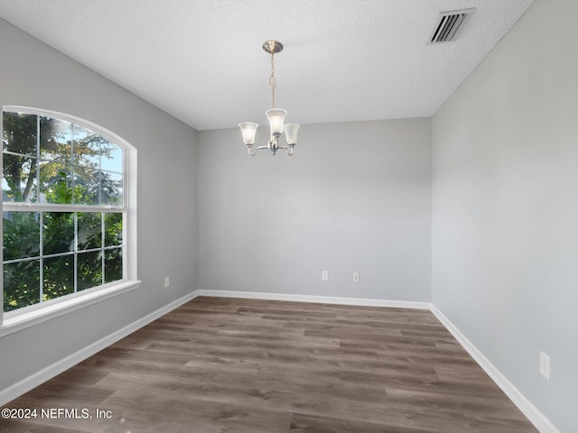 unfurnished room featuring dark hardwood / wood-style flooring, a textured ceiling, and a chandelier