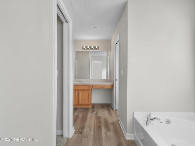 hall with a textured ceiling, light wood-type flooring, and sink