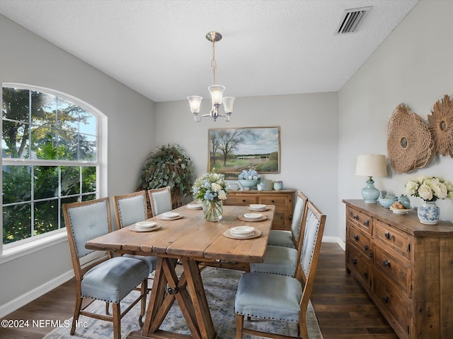 dining space with a textured ceiling, dark wood-type flooring, and a chandelier