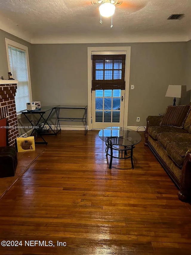 living room featuring a textured ceiling, a fireplace, and dark hardwood / wood-style flooring