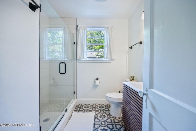 bathroom featuring tile patterned flooring, vanity, toilet, and walk in shower