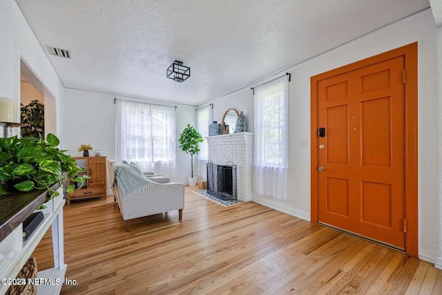 living room with a fireplace, light hardwood / wood-style floors, and a textured ceiling