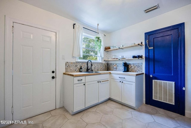 kitchen with white cabinetry, sink, and light tile patterned floors