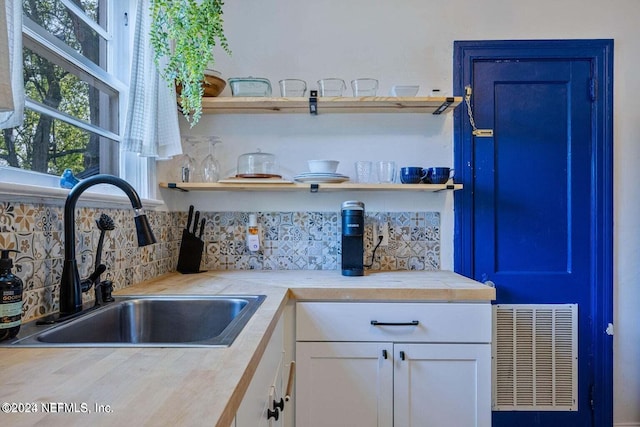 kitchen featuring backsplash, butcher block counters, sink, and white cabinets